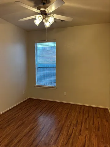 a view of a room with wooden floor a ceiling fan and a window