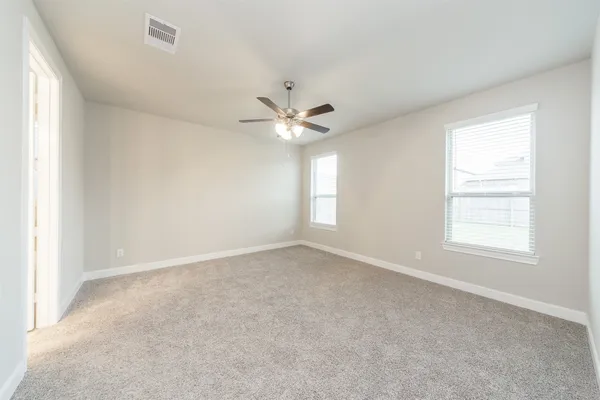 an empty room with windows and ceiling fan