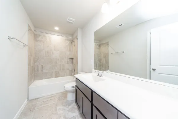 a bathroom with a granite countertop sink a toilet a mirror and bathtub