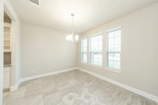 an empty room with chandelier fan and windows