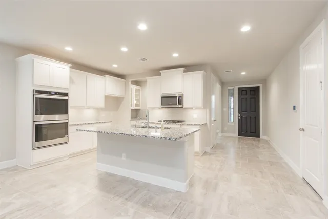 a large kitchen with stainless steel appliances kitchen island granite countertop a stove a sink and a refrigerator