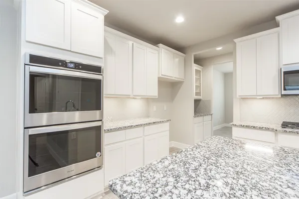 a kitchen with granite countertop white cabinets and appliances