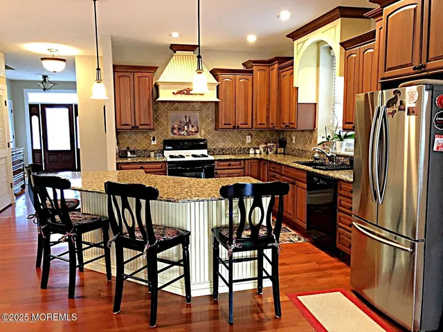 a kitchen with stainless steel appliances a dining table chairs stove and refrigerator
