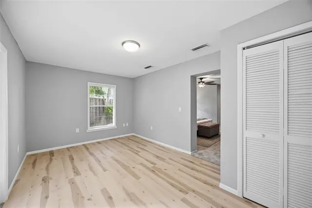 a view of empty room with wooden floor and fan