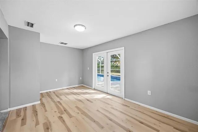 an empty room with wooden floor and windows
