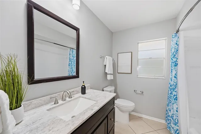 a bathroom with a granite countertop sink toilet and mirror