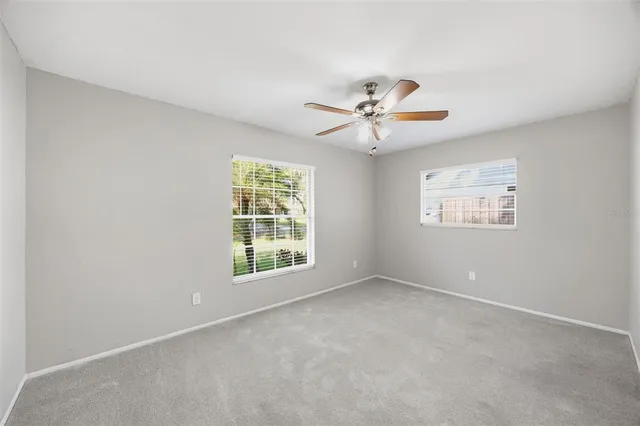an empty room with windows and fan