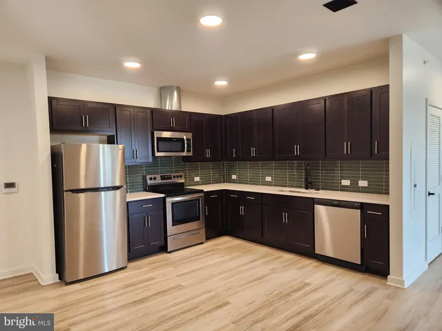 a kitchen with stainless steel appliances granite countertop a refrigerator stove a sink and dishwasher with wooden floor