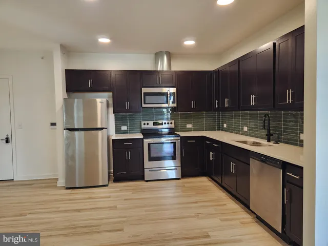 a kitchen with stainless steel appliances granite countertop a refrigerator stove a sink and dishwasher with wooden floor