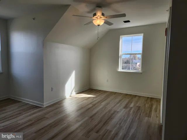 an empty room with wooden floor chandelier fan and windows