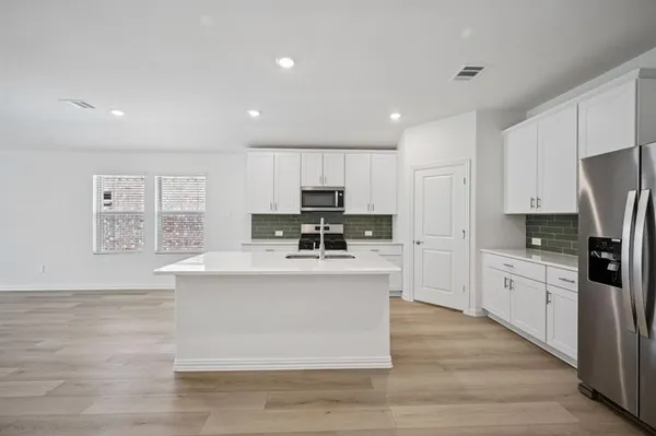 a kitchen with stainless steel appliances granite countertop a refrigerator sink and white cabinets