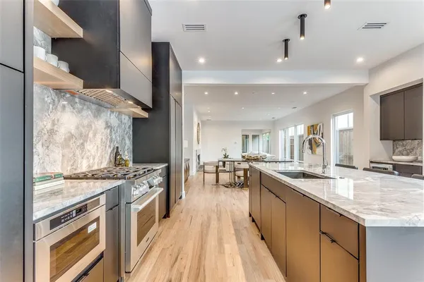 a kitchen with stainless steel appliances granite countertop a stove top oven a sink dishwasher a dining table and chairs with wooden floor