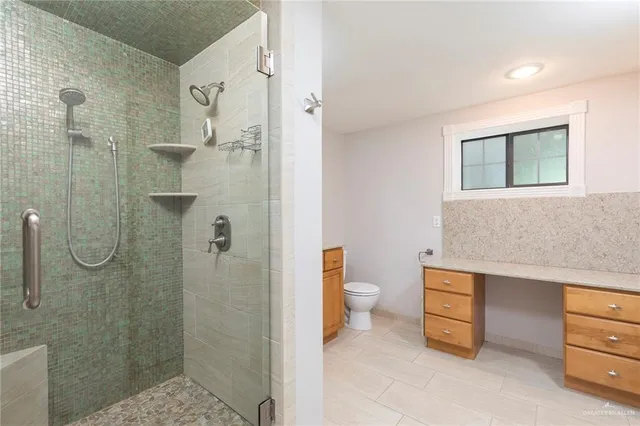 a bathroom with a granite countertop shower a toilet and a sink