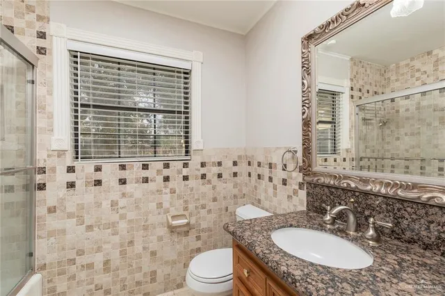 a bathroom with a granite countertop sink toilet a mirror and shower