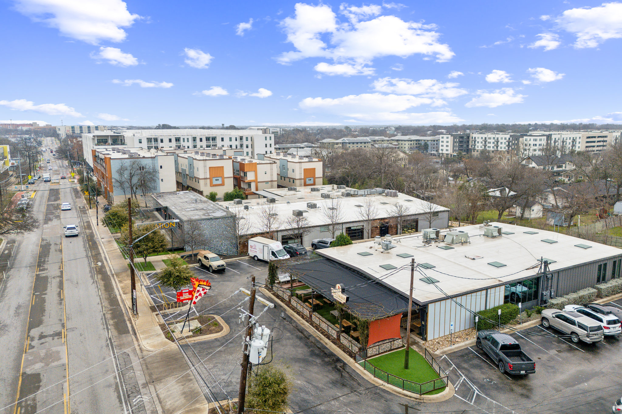 2827 Manor Road, Unit 3104 Austin, TX 78722 - Photo 25 of 30 An aerial perspective showcases a bustling commercial street with varied building styles and ample parking.
