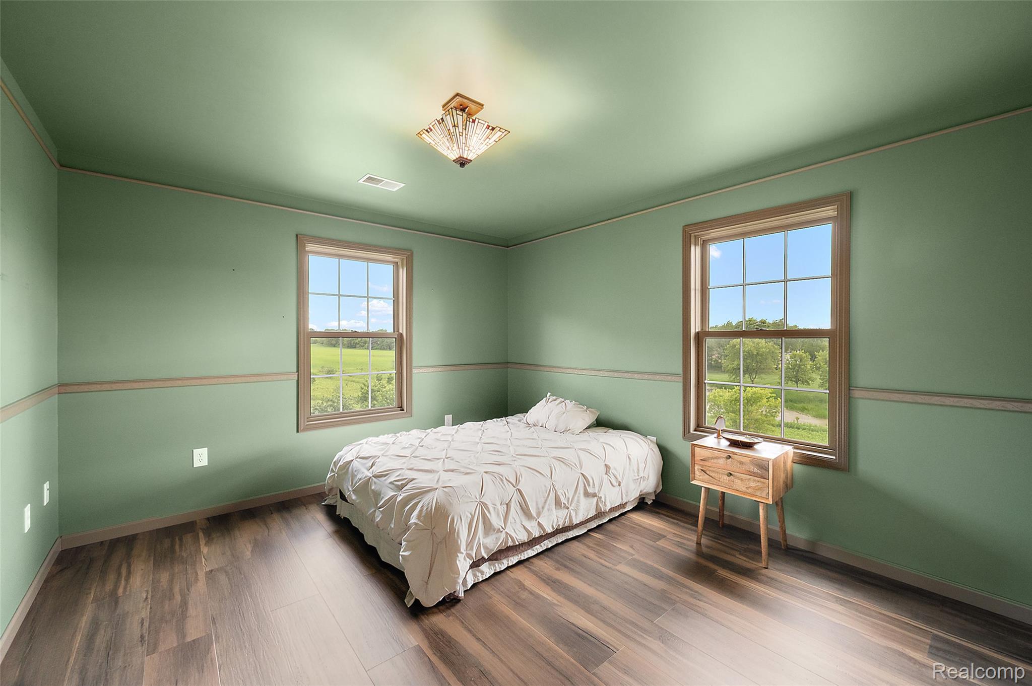 5035 Hidden Ridge Road Metamora, MI 48455 - Photo 38 of 65 Spacious room featuring wood-finish flooring, two large windows, a decorative ceiling light fixture, and a two-tone wall treatment with a chair rail