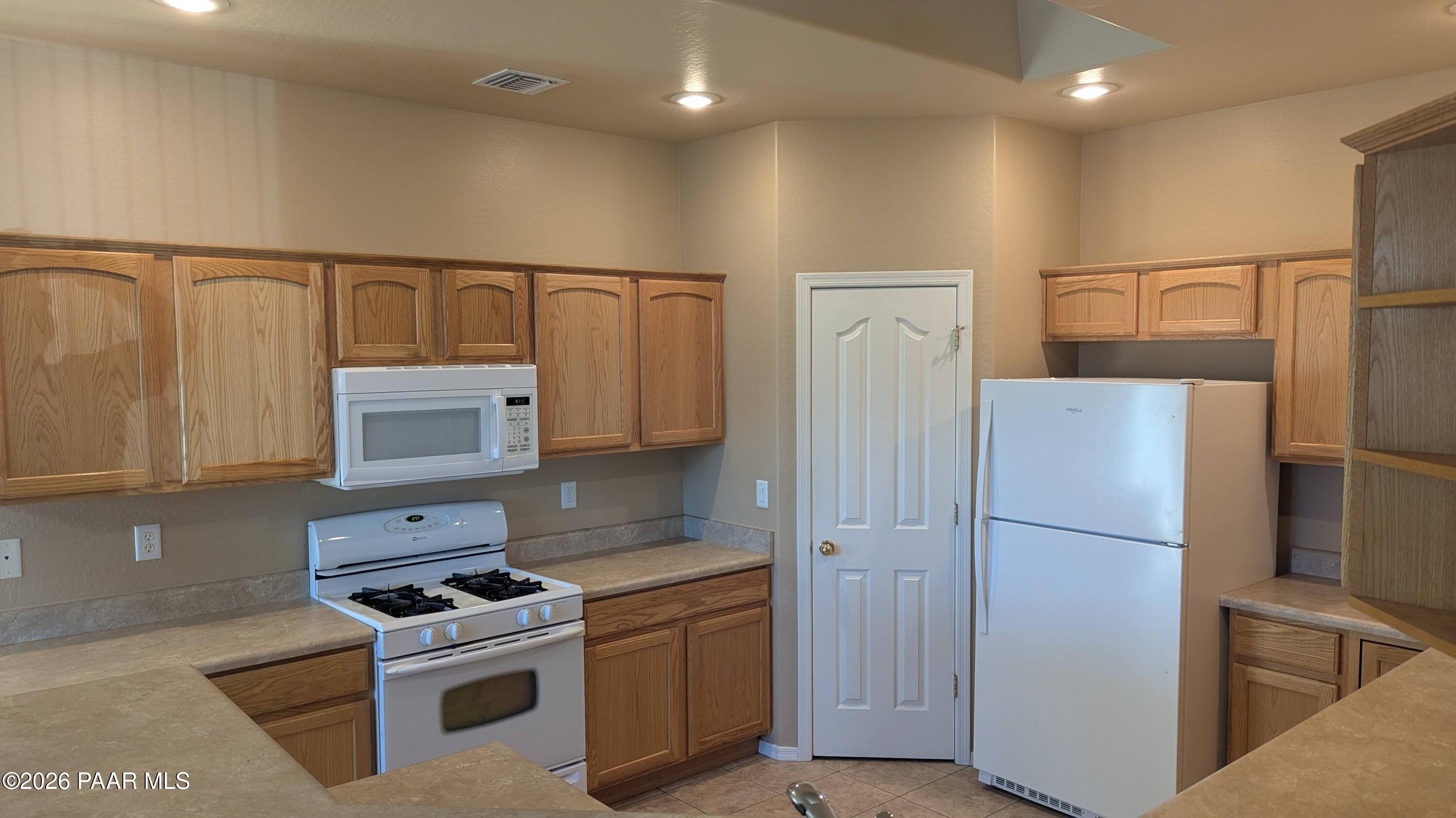3416 North Victor Road, Unit 1 Prescott Valley, AZ 86314 - Photo 9 of 27 a kitchen with a refrigerator a stove top oven and cabinets
