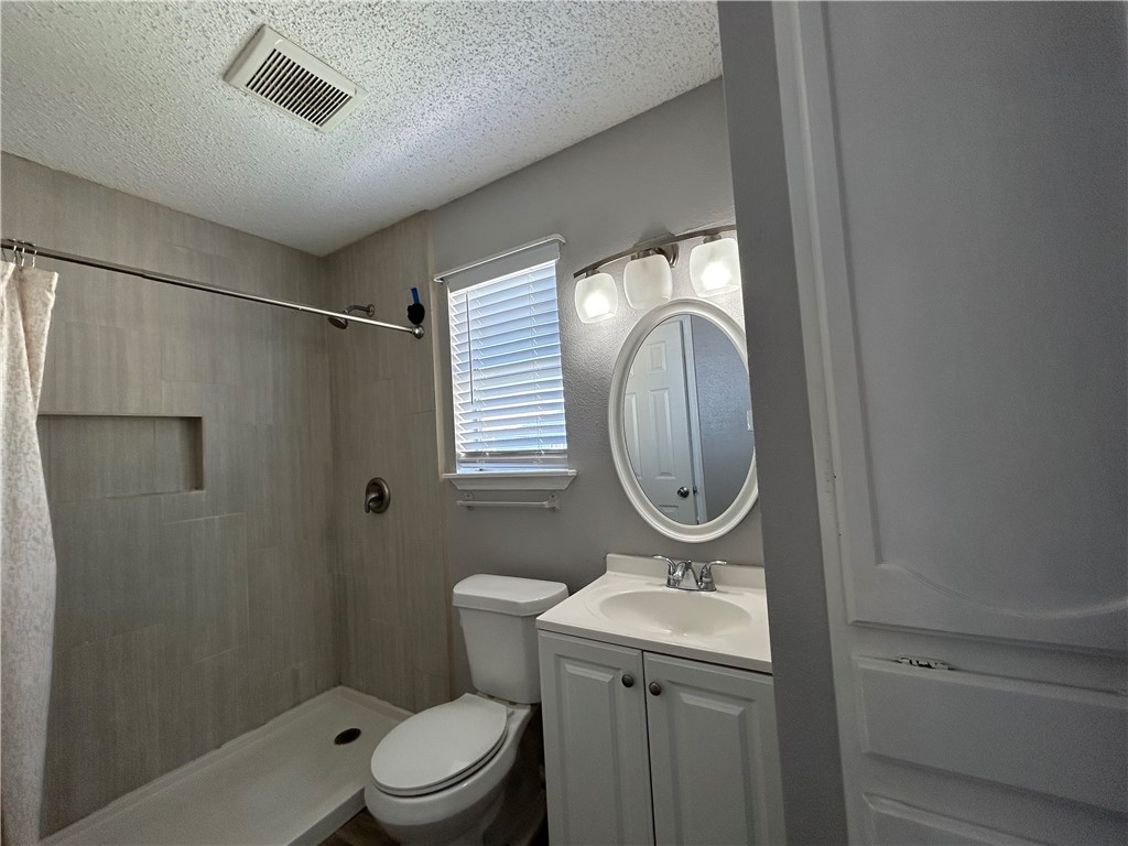 6702 Everhart Road, Unit I105 Corpus Christi, TX 78413 - Photo 10 of 19 a bathroom with a toilet a sink and a mirror
