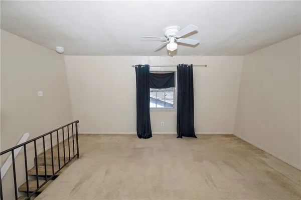 a view of an empty room with chandelier fan