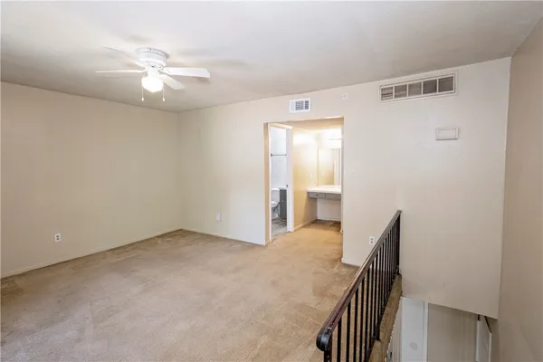 a view of an empty room with wooden floor and a ceiling fan