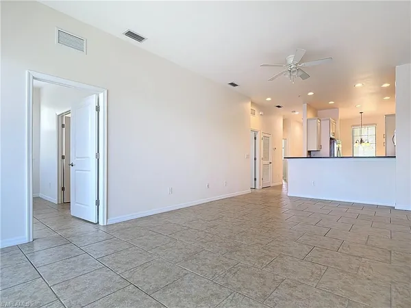 an empty room with a kitchen and a chandelier fan