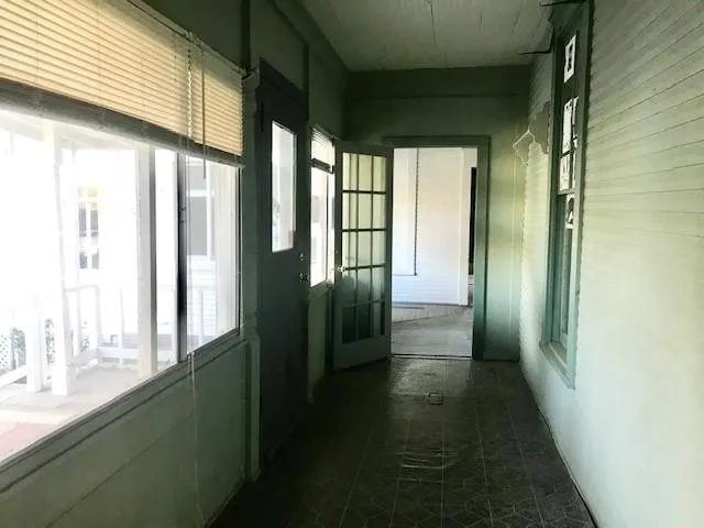 an empty room with wooden floor cabinet and windows