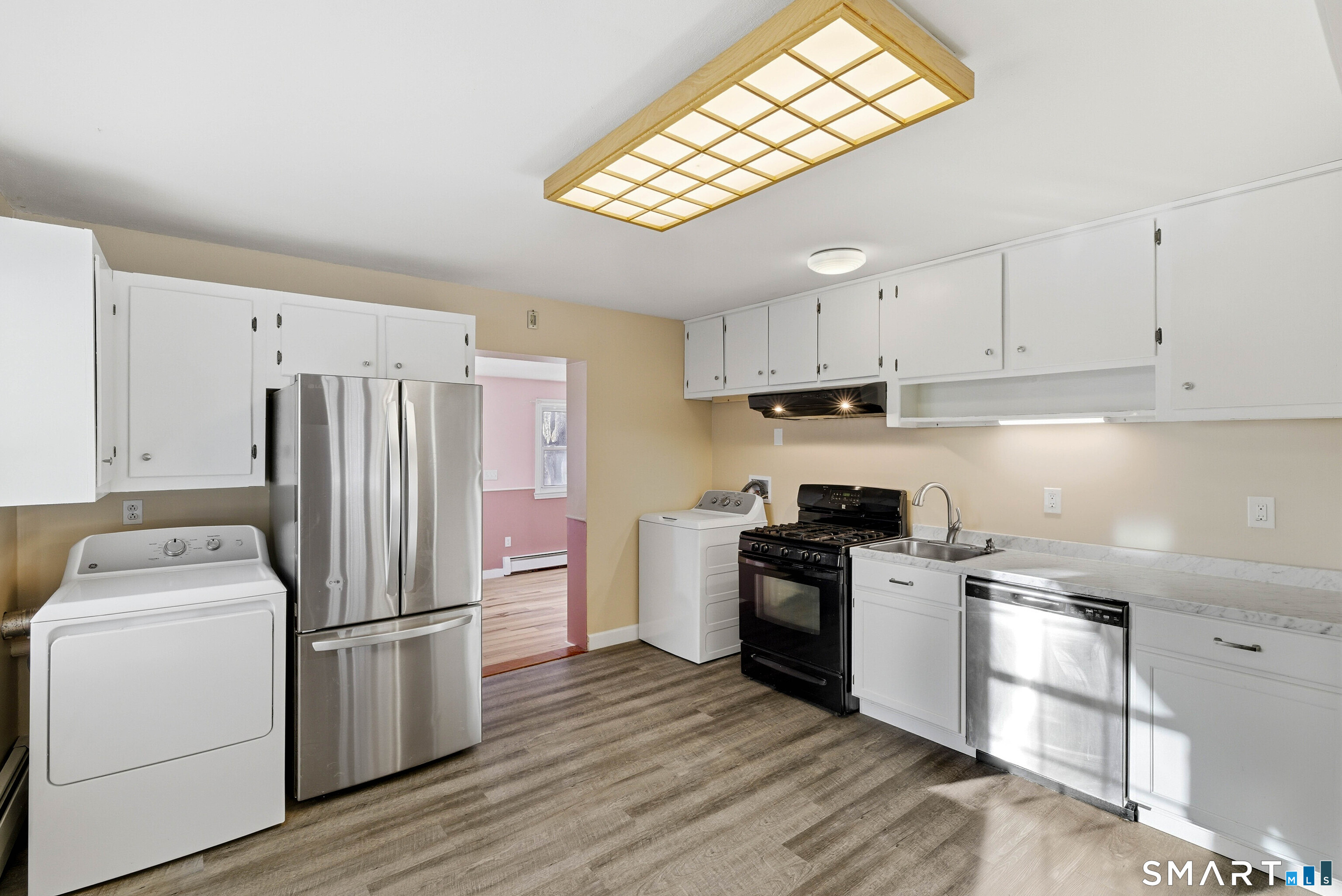 57 Hellstrom Road East Haven, CT 06512 - Photo 9 of 36 a kitchen with a refrigerator a sink dishwasher a stove and white cabinets with wooden floor