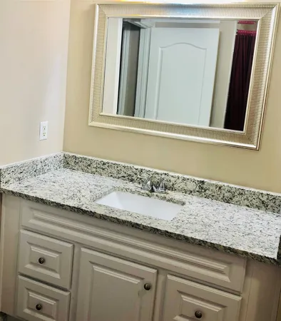 a view of a granite countertop white vanity and a mirror