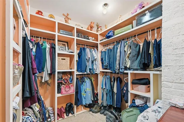 a view of walk in closet with clothes and shoes