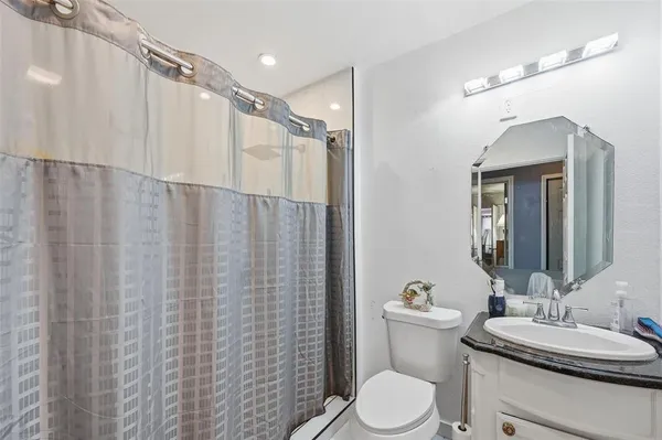a bathroom with a sink a toilet a mirror and shower curtain