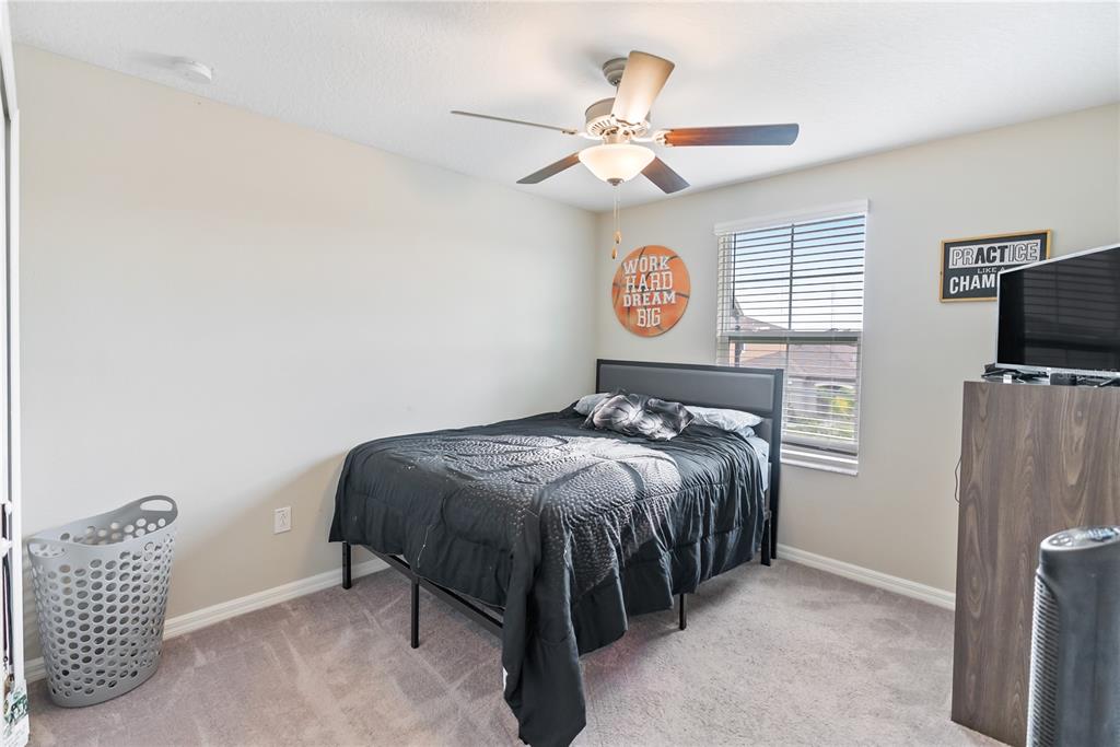 9313 Lemon Drop Loop Ruskin, FL 33573 - Photo 19 of 29 a bedroom with a bed and a chandelier