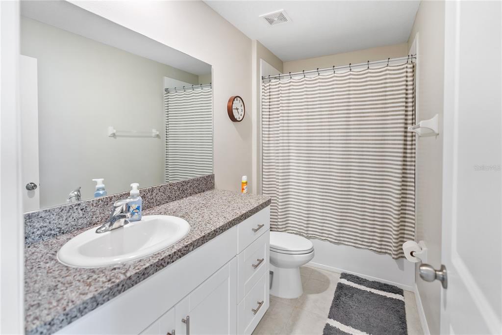 9313 Lemon Drop Loop Ruskin, FL 33573 - Photo 21 of 29 a bathroom with a granite countertop sink toilet a mirror a shower and a window