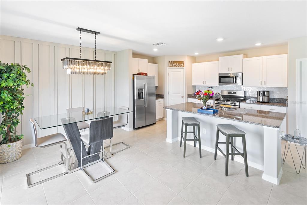 9313 Lemon Drop Loop Ruskin, FL 33573 - Photo 8 of 29 a kitchen with stainless steel appliances kitchen island granite countertop a refrigerator a stove a sink a dining table and chairs with wooden floor