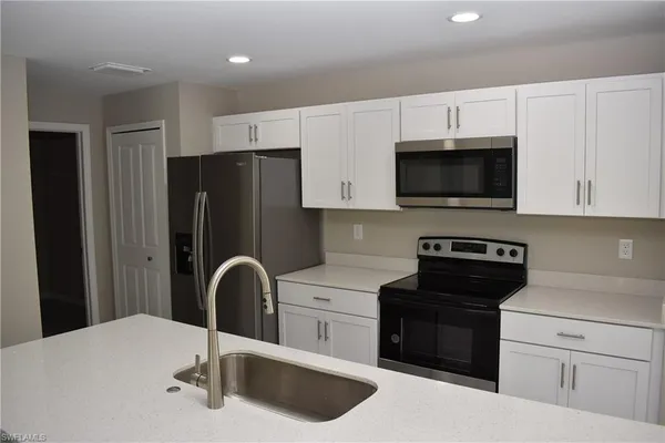 a kitchen with stainless steel appliances kitchen island a sink a microwave a refrigerator and cabinets