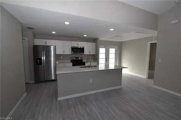 a view of a living room a kitchen with a sink a microwave and wooden floor