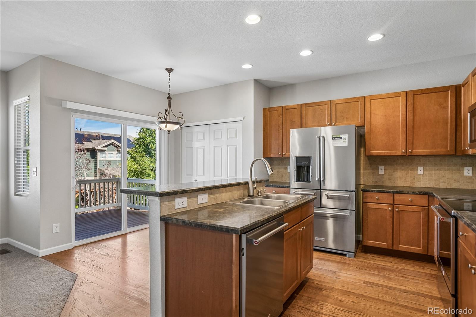 5031 South Rome Street Aurora, CO 80015 - Photo 8 of 39 a kitchen with stainless steel appliances granite countertop a stove a refrigerator a sink and white cabinets with wooden floor