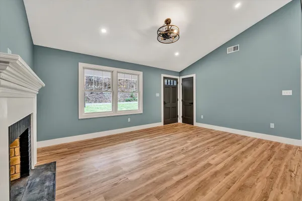 a view of an empty room with window and wooden floor