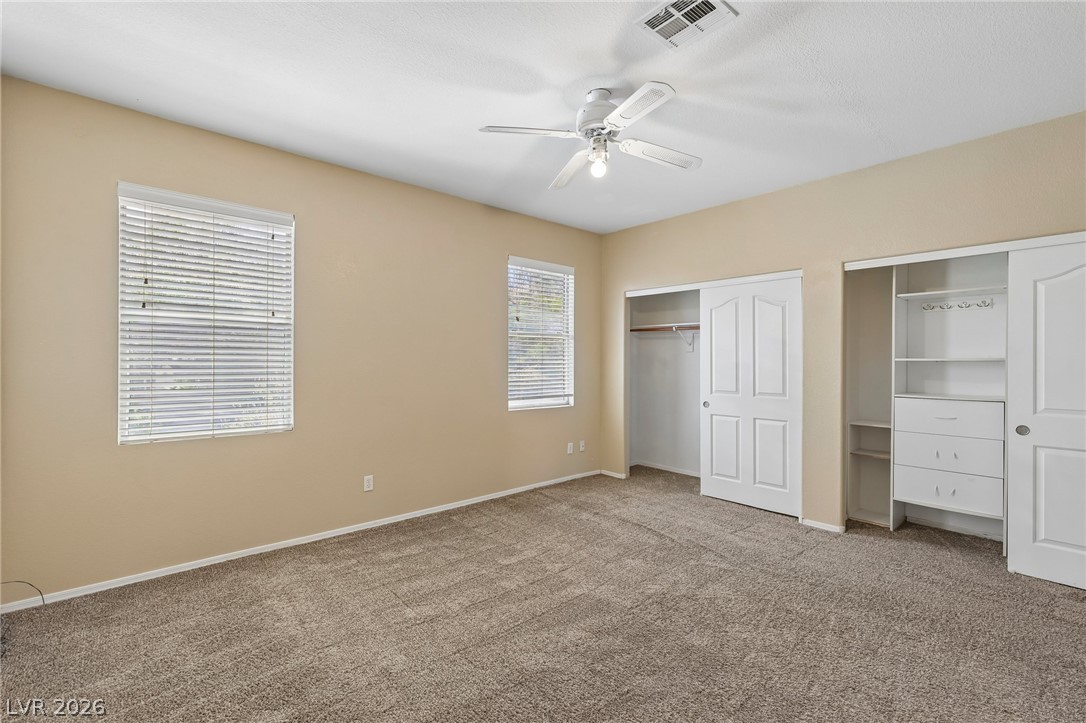 1727 Millstream Way Henderson, NV 89074 - Photo 25 of 46 A well-proportioned bedroom features soft carpeting, window treatments, and practical closet storage solutions.