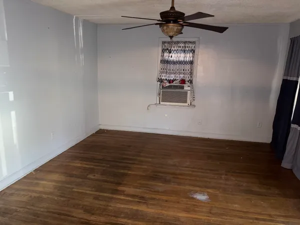 a view of a room with wooden floor a ceiling fan and window