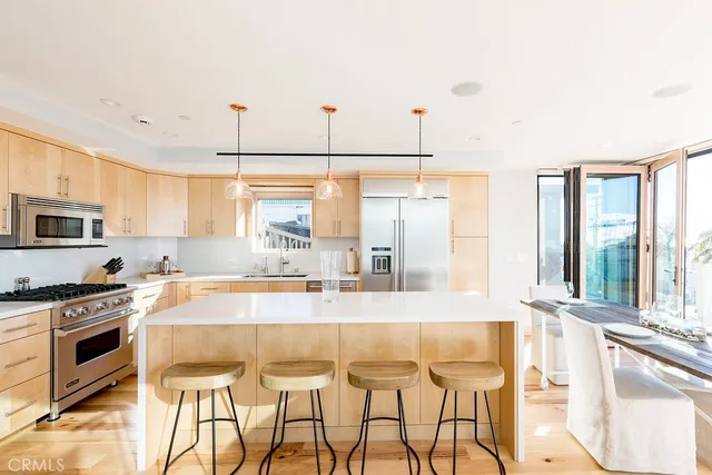 a kitchen with stainless steel appliances granite countertop a stove a sink and a refrigerator with wooden floor