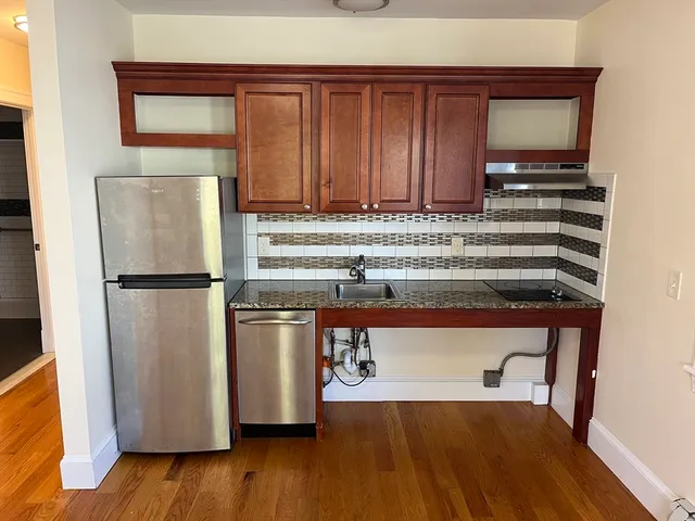 a kitchen with a refrigerator a stove and a wooden floor