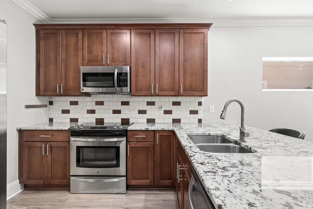 a kitchen with granite countertop wooden cabinets a sink and stainless steel appliances