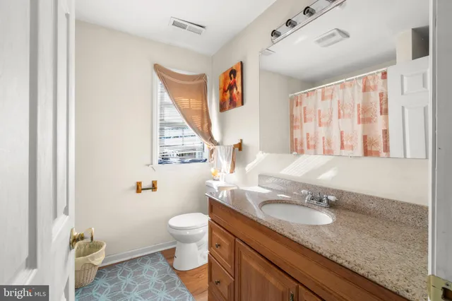 a bathroom with a granite countertop sink mirror vanity and toilet