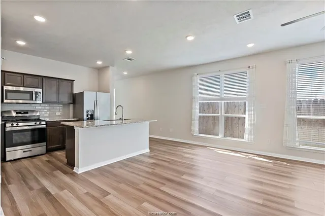 a kitchen with a sink wooden floor and stainless steel appliances
