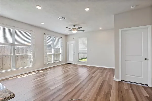 a view of an empty room with a window and wooden floor