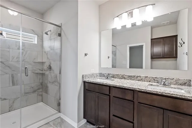 a bathroom with a granite countertop sink a mirror and a shower