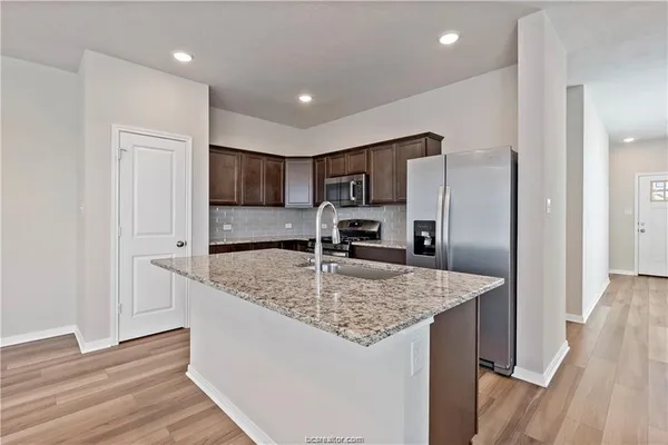 a kitchen with stainless steel appliances granite countertop a sink refrigerator and microwave