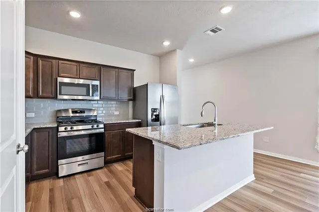 a kitchen with stainless steel appliances granite countertop a stove a sink and a microwave