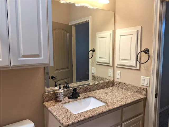 a bathroom with a granite countertop bathtub sink vanity mirror and toilet