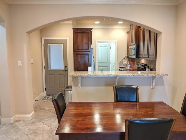 a kitchen with stainless steel appliances granite countertop a refrigerator a stove and a sink with wooden cabinets